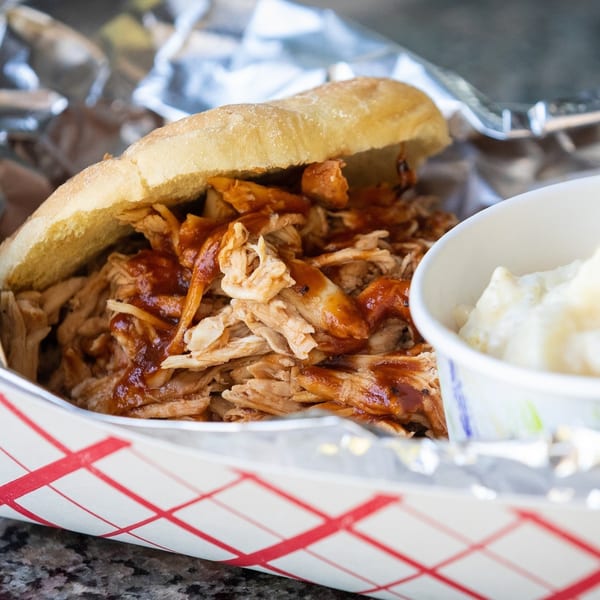 A Larry J's BBQ Cafe pulled chicken sandwich with barbecue sauce and a side of coleslaw.